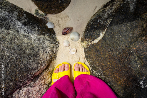 Female feet in yellow sleepers on the beach photo