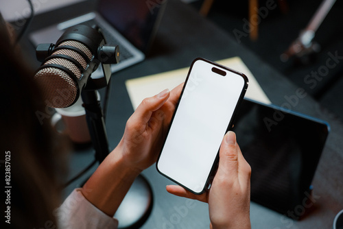 Women's hands with a mobile phone in the studio with a microphone photo