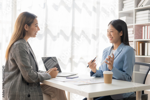 Wallpaper Mural Two young Asian businesswomen work on laptop computers in the office with reports. Colleagues discuss financial data in document analysis of new marketing projects. Torontodigital.ca