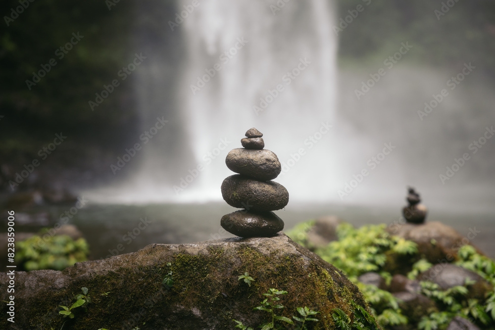 © Pedro Merino/Stocksy - stack of stones balanced in front of a waterfall