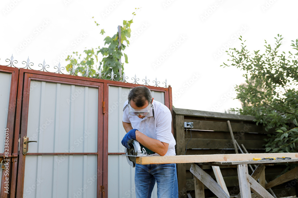 a man processes wood in the yard
