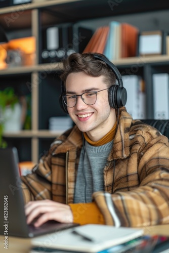 A man sitting at a desk with a laptop and headphones. Suitable for business and technology concepts