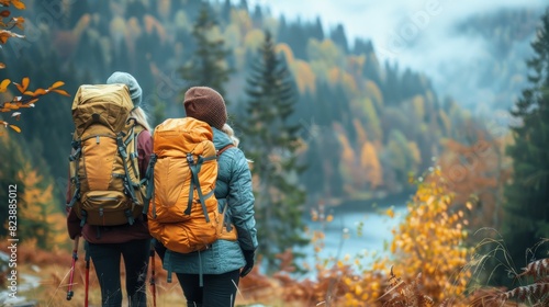 Hikers overlooking a scenic autumn landscape with foggy mountains