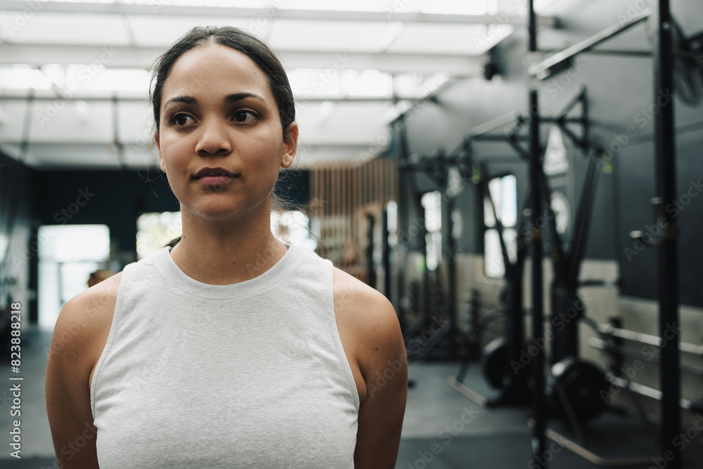Serious sportswoman in tank top looking away in gym Serious sportswoman in tank top looking away in gym