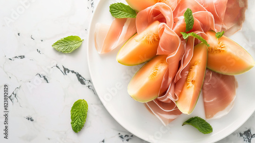 Sliced prosciutto and melon on a white plate, viewed from above.