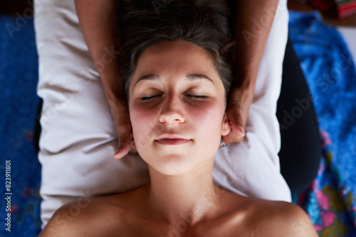 Woman, relax and eyes closed with head massage in spa above with masseuse for wellness with comfort or care. Peace, mind and deep tissue with gentle hands on patient for balance of energy in Germany.