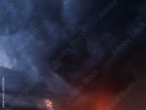 Ominous storm clouds fill the sky at dusk, contrasting with patches of orange light and intense dark blue colors, creating a dramatic and moody atmosphere.