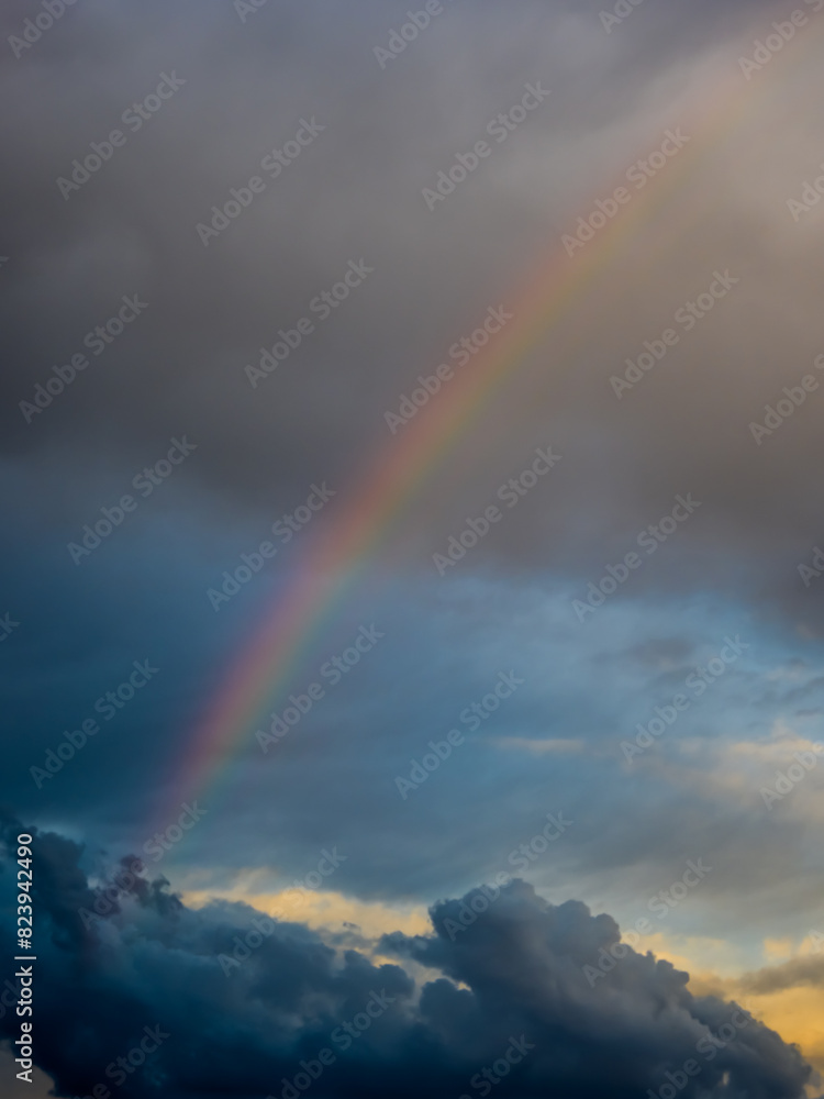 Multicolored rainbow among dark rain clouds