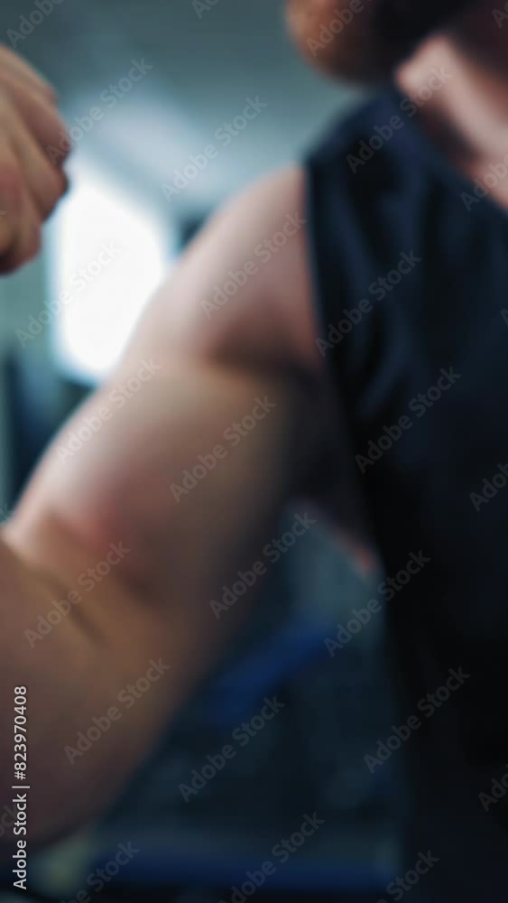 Close-up muscles on man's arm in sports club. Strong bodybuilder in sportswear showing his biceps in fitness center. Vertical video Close-up muscles on man's arm in sports club. Strong bodybuilder in sportswear showing his biceps in fitness center. Vertical video