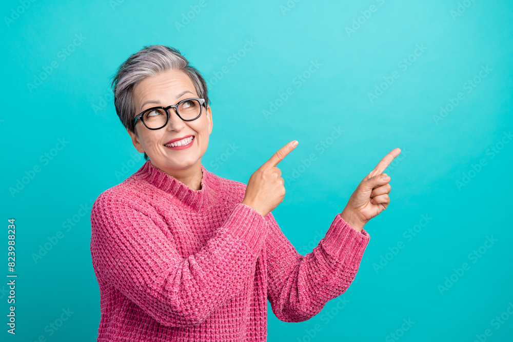 Photo of friendly retired person dressed knitwear sweater in glasses look directing at logo empty space isolated on teal color background Photo of friendly retired person dressed knitwear sweater in glasses look directing at logo empty space isolated on teal color background