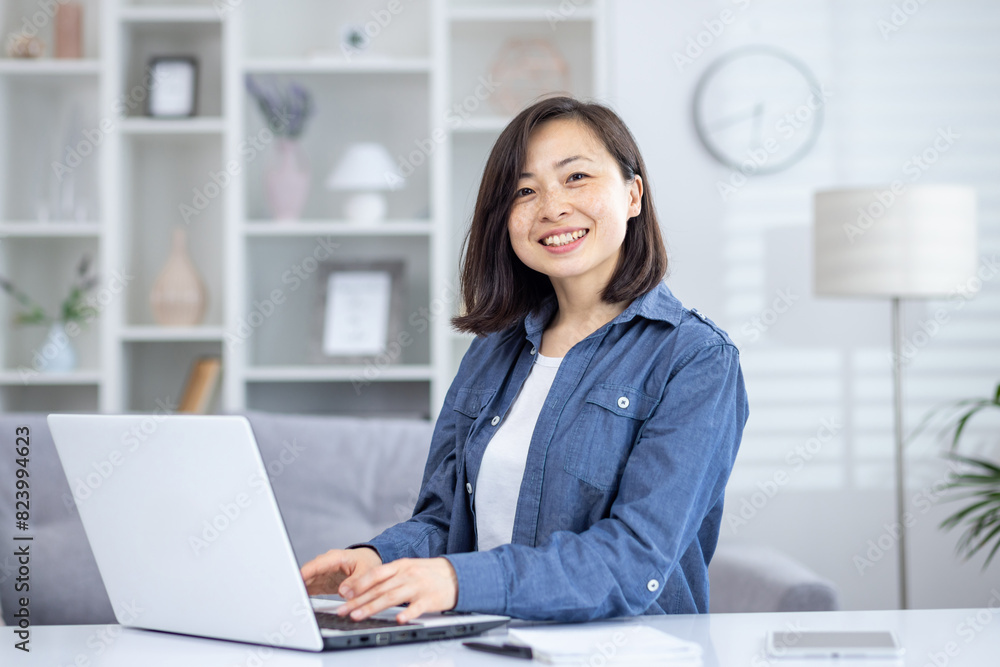 Happy woman working on a laptop at home office. Comfortable and modern home office environment with cozy decor, bright and cheerful atmosphere. Happy woman working on a laptop at home office. Comfortable and modern home office environment with cozy decor, bright and cheerful atmosphere.