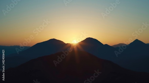 Mountains captured in silhouette at dawn with a soft sunrise in the background