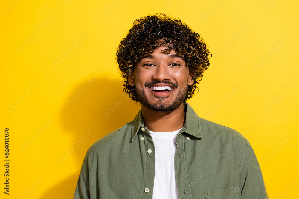 Portrait photo of young funny very optimistic friendly smiling hispanic guy in khaki shirt isolated on yellow color background Portrait photo of young funny very optimistic friendly smiling hispanic guy in khaki shirt isolated on yellow color background