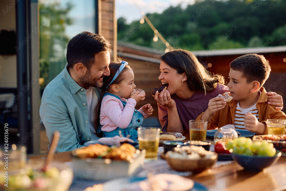 Happy family having fun while eating donuts at picnic table on patio. Happy family having fun while eating donuts at picnic table on patio.