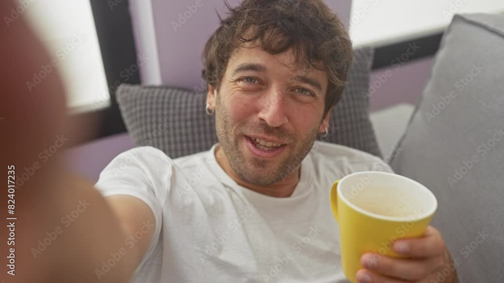 Young hispanic man enjoying a video call while relaxing at home with a cup of coffee in the living room, showing a happy and casual moment indoors. Young hispanic man enjoying a video call while relaxing at home with a cup of coffee in the living room, showing a happy and casual moment indoors.