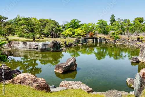 Japanese garden with water pond, rocks and green plants at Nijo Castle, Japan.
