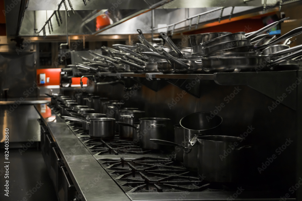 Naklejka premium Close up of stainless steel utensils - pots, pans, stoves. cooking equipment in a restaurant kitchen. Training equipment for student chefs, cooks.