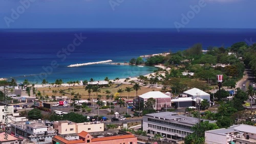 Traffic in a busy street of Montego Bay, with the vibrant cityscape and turquoise waters in the background, in tropical surroundings photo