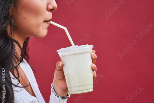 Woman sipping a smoothie against a red background