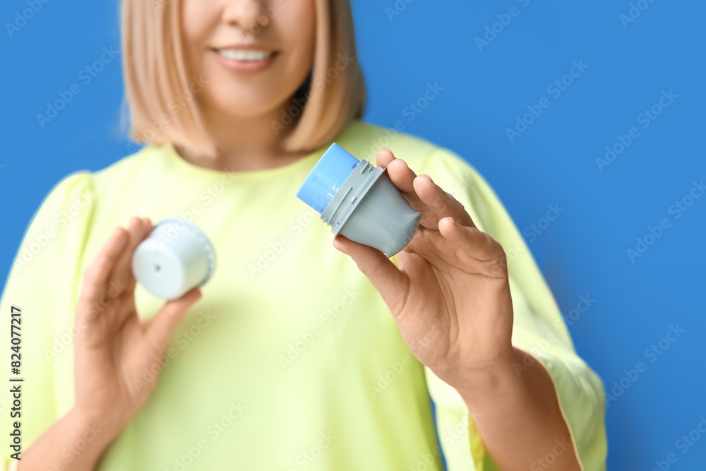 Woman with glucose sensor for measuring blood sugar level and applicator on blue background. Diabetes concept Woman with glucose sensor for measuring blood sugar level and applicator on blue background. Diabetes concept