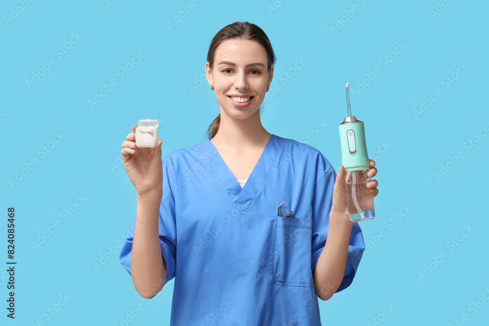 Female dentist with oral irrigator and dental floss on blue background Female dentist with oral irrigator and dental floss on blue background
