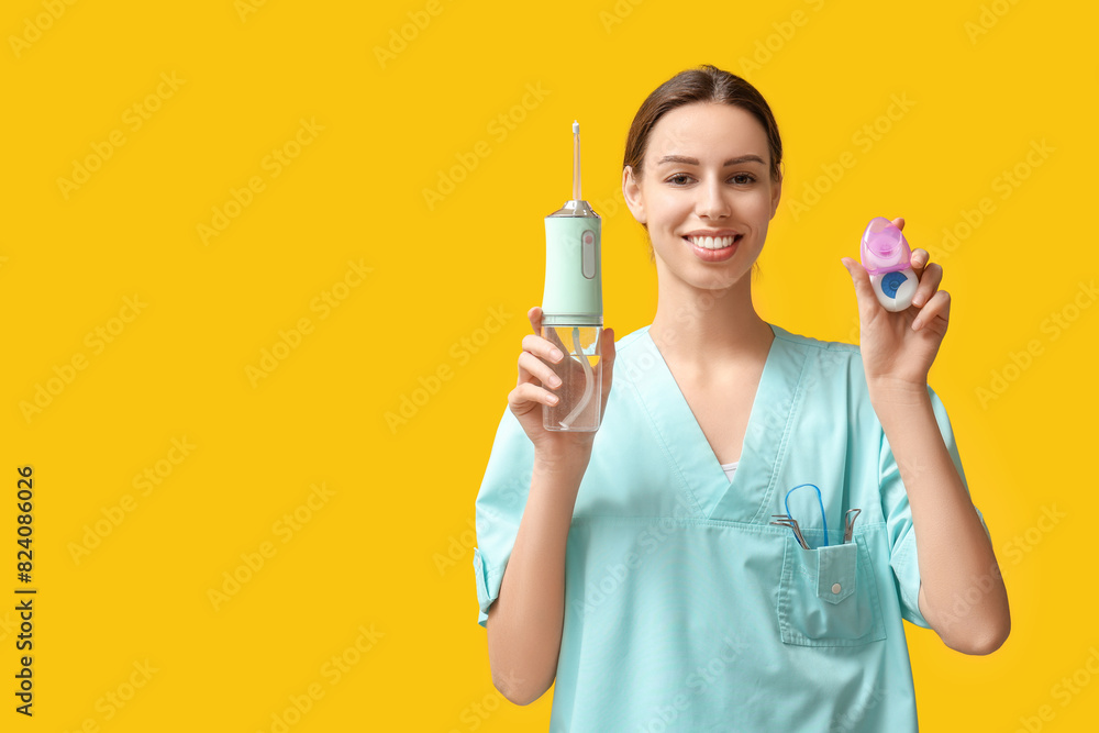 Female dentist with oral irrigator and dental floss on yellow background Female dentist with oral irrigator and dental floss on yellow background