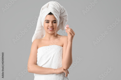 Happy smiling young woman in towel with crystal deodorant on white background