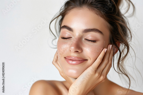 Young woman with fresh  glowing skin applying facial cream