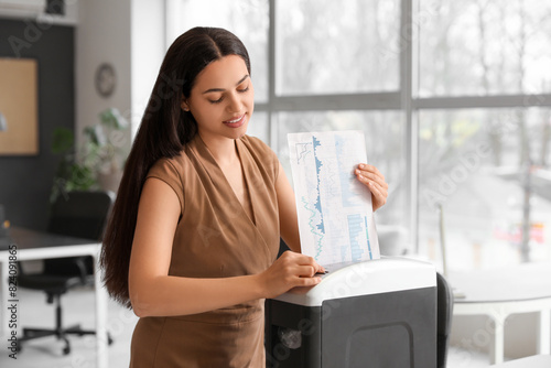 Slika na platnu Young secretary destroying documents using shredder in office