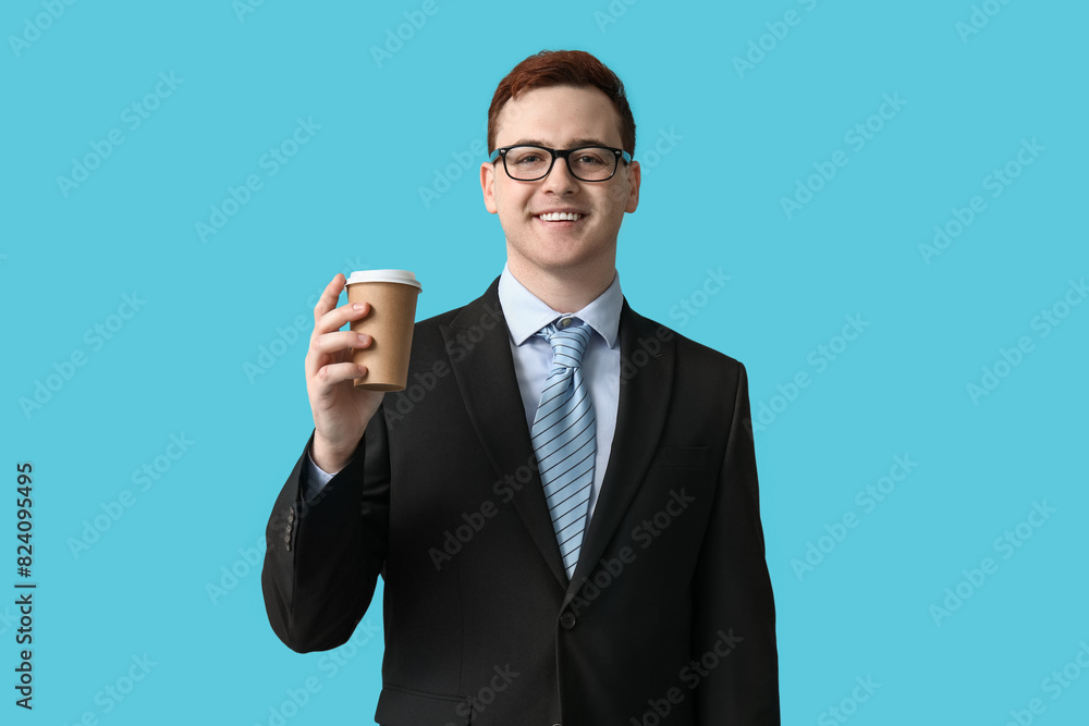 Young man in eyeglasses holding paper cup of coffee on blue background Young man in eyeglasses holding paper cup of coffee on blue background