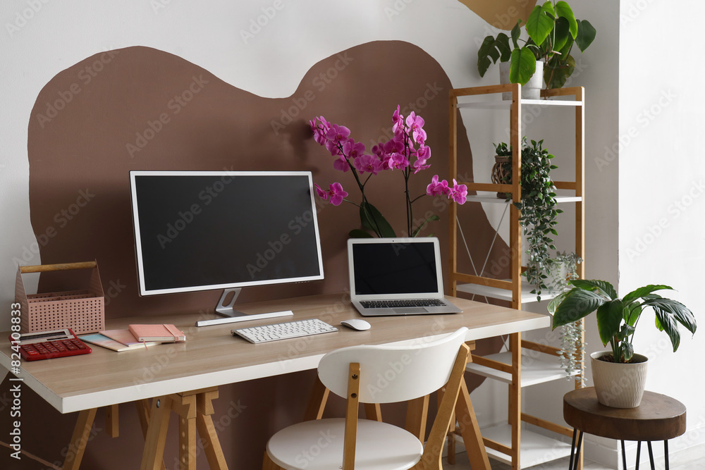 Fototapeta premium Workplace with computer, laptop and orchid flower in stylish office