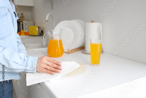 Woman wiping spilled juice with paper towel on counter in kitchen, closeup © Pixel-Shot