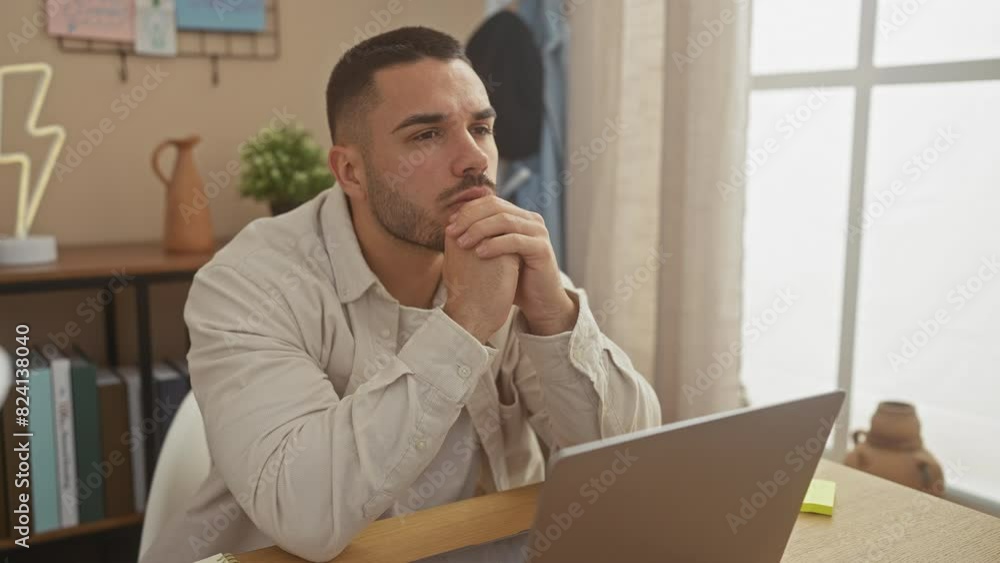 Pensive young hispanic man using laptop in a well-lit cozy living room, embodying modern work from home. Pensive young hispanic man using laptop in a well-lit cozy living room, embodying modern work from home.