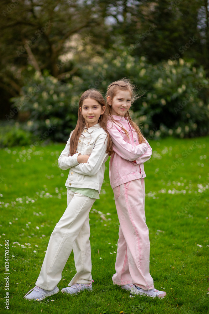 Two friendly girls in light-toned clothing with smiles enjoying Two friendly girls in light-toned clothing with smiles enjoying