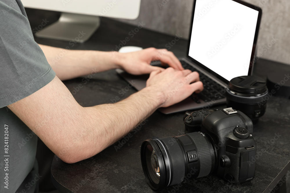 Photographer using laptop at dark table with camera, closeup Photographer using laptop at dark table with camera, closeup