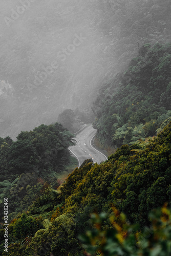 Photography A foggy mountain landscape with a winding road cutting through the middle, disappearing into the mist