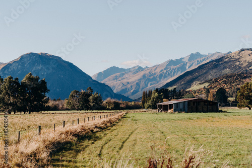 Grassy Field With Mountains in the Background and An Old Dilapidated Barn