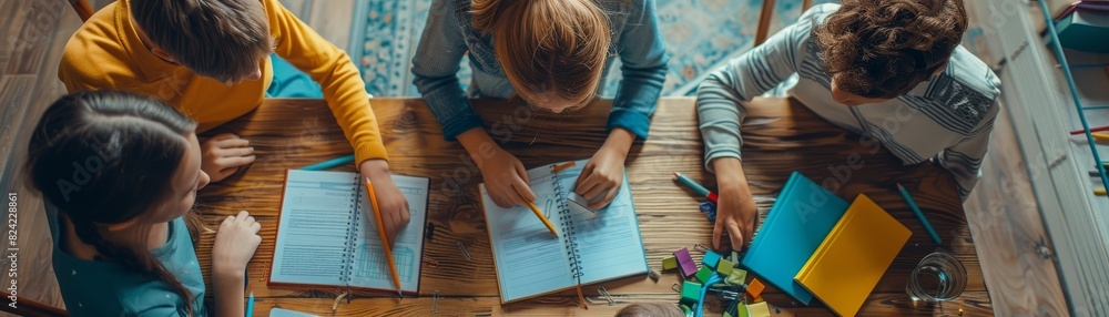 A group of children studying together at a table, collaborating on an educational project with books and notebooks. A group of children studying together at a table, collaborating on an educational project with books and notebooks.