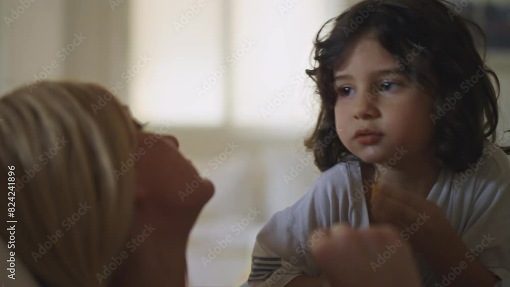 A young boy engages in a conversation with his mother while indoors. Both are comfortably dressed, emphasizing a warm and intimate dialogue. A young boy engages in a conversation with his mother while indoors. Both are comfortably dressed, emphasizing a warm and intimate dialogue.