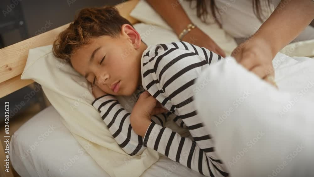 A young boy sleeping peacefully in a striped shirt, comforted by a woman's hand, signifies love and care in a cozy bedroom setting. A young boy sleeping peacefully in a striped shirt, comforted by a woman's hand, signifies love and care in a cozy bedroom setting.