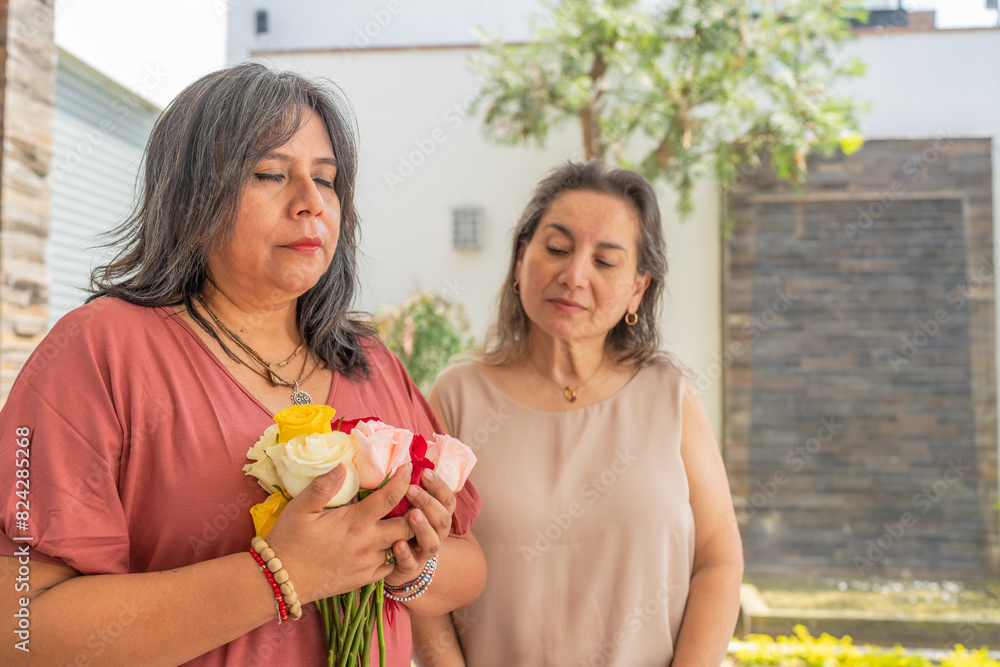 Woman hugging a bouquet of roses and her friend watching her Woman hugging a bouquet of roses and her friend watching her