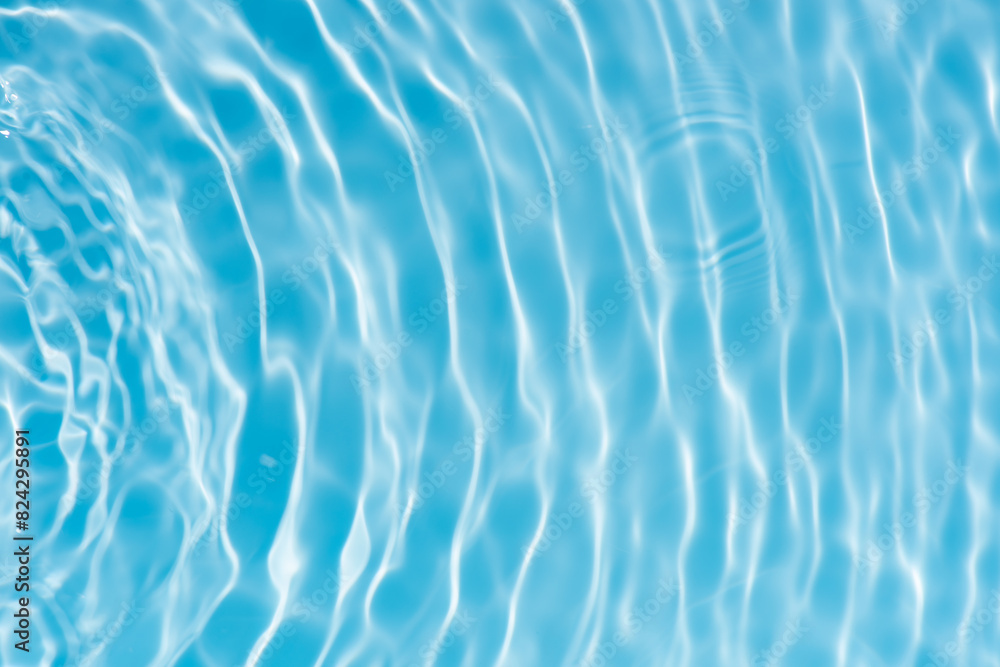 Obraz premium Blue water with ripples on the surface. Defocus blurred transparent blue colored clear calm water surface texture with splashes and bubbles. Water waves with shining pattern texture background.