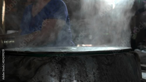 Vietnamese woman making rice paper or banh trang from rice flour, coal stove with smoke rises for circle girdle cake handmade, Ben Tre, Viet Nam photo