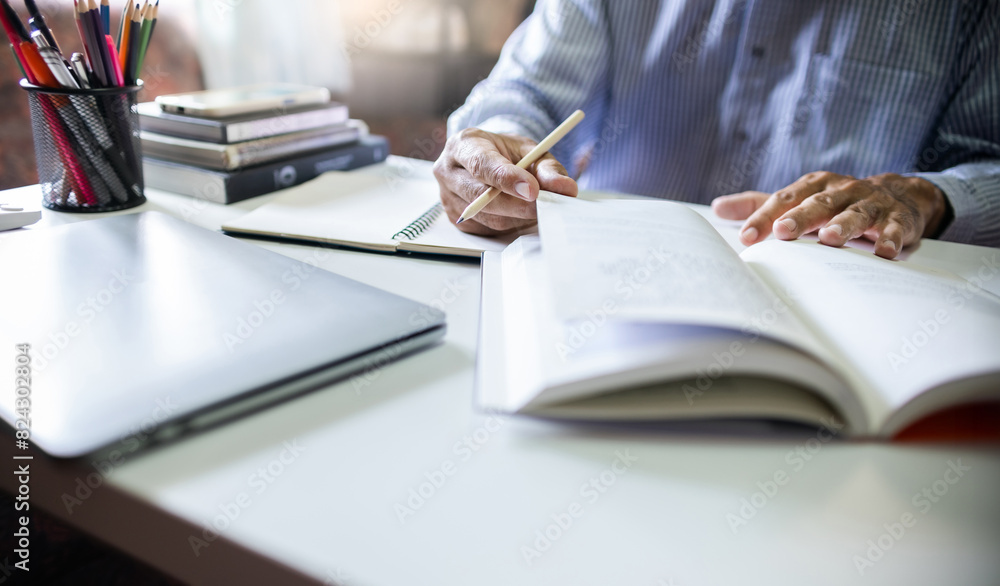 Home office of asian businessman working and learning marketing plan with business books