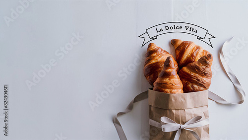 Freshly baked French buttery flaky croissants in brown paper bag on white background. Minimalist creative food banner with copy space photo