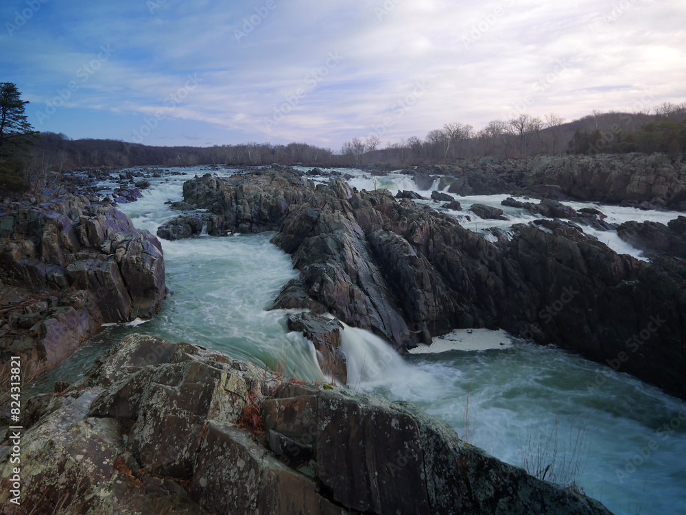 Strong water rapids waterfall in Great Falls National Park, Virginia side in winter. Overcast cloudy sky, flowing water.