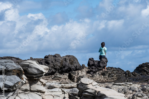 Woman tourist enjoying the view at Dragon’s Teeth, fascinating trachyte lava rock geology where it flows into the Pacific Ocean, Makalua-Puna Point, Maui, Hawaii
 photo
