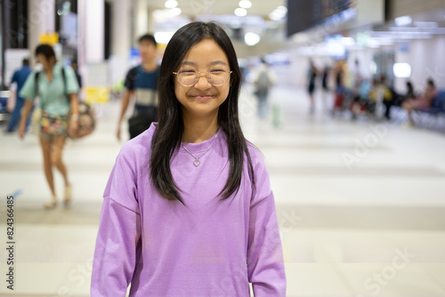 Asian girl with long hair wearing eyeglasses smiling brightly at the airport