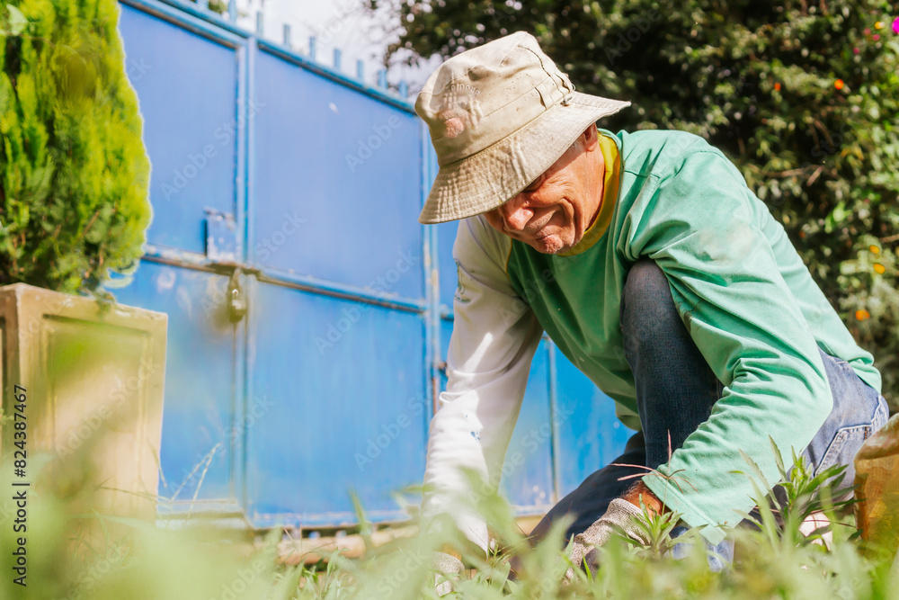Older Latino man with hat and gloves, working the land on his farm. Nature and garden. Copy space. Older Latino man with hat and gloves, working the land on his farm. Nature and garden. Copy space.