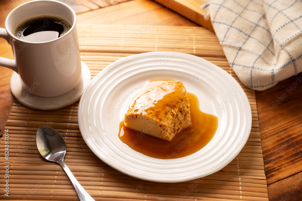 homemade flan dessert, also known as creme caramel, caramel custard pudding or egg custard, served on white plate on wooden table. homemade flan dessert, also known as creme caramel, caramel custard pudding or egg custard, served on white plate on wooden table.
